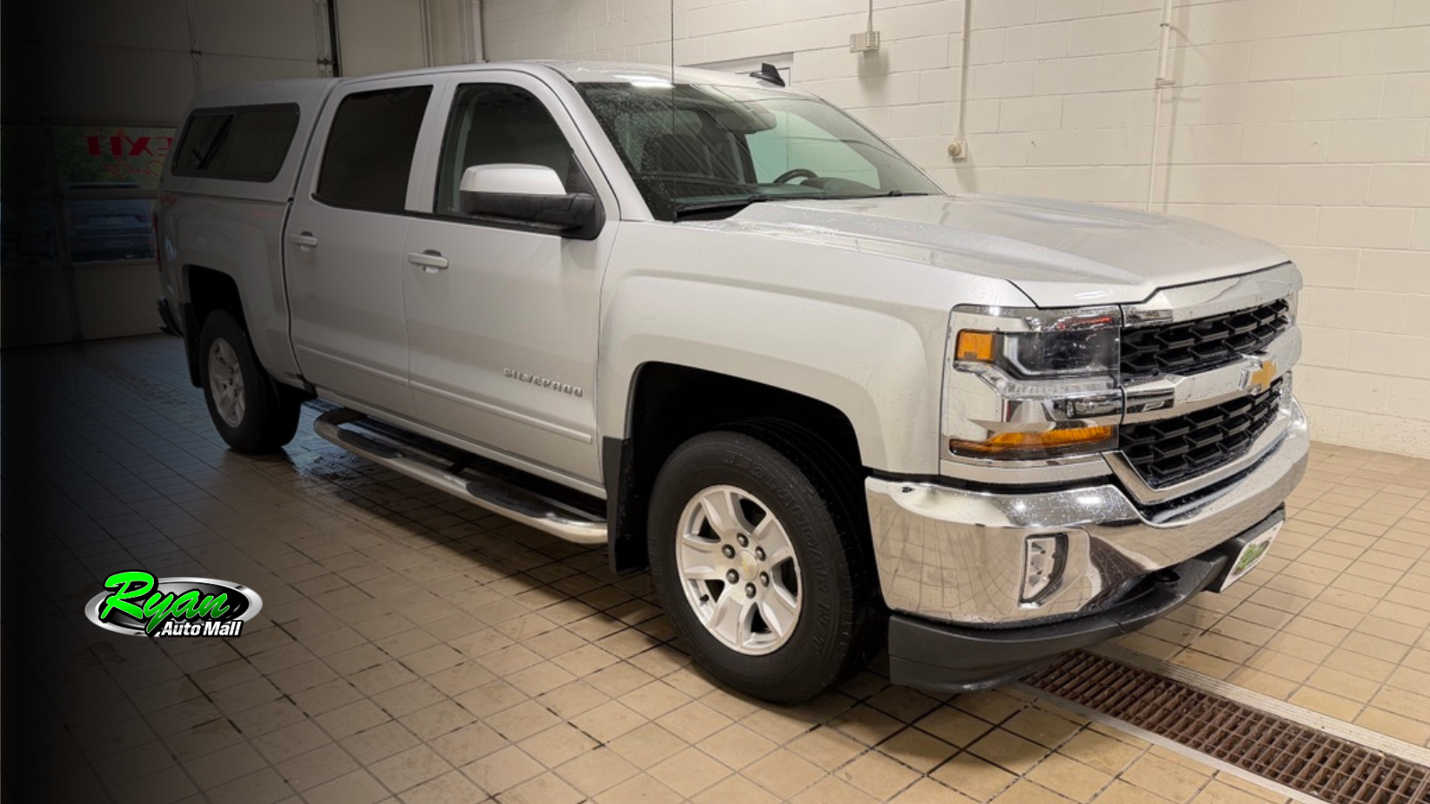 Silver 2016 Chevrolet Silverado LT crew cab pickup with a bed topper and running boards at Ryan Auto Mall.
